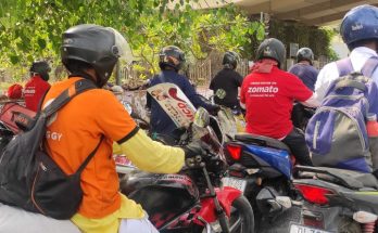 delivery boys under a tree shade in a traffic jam